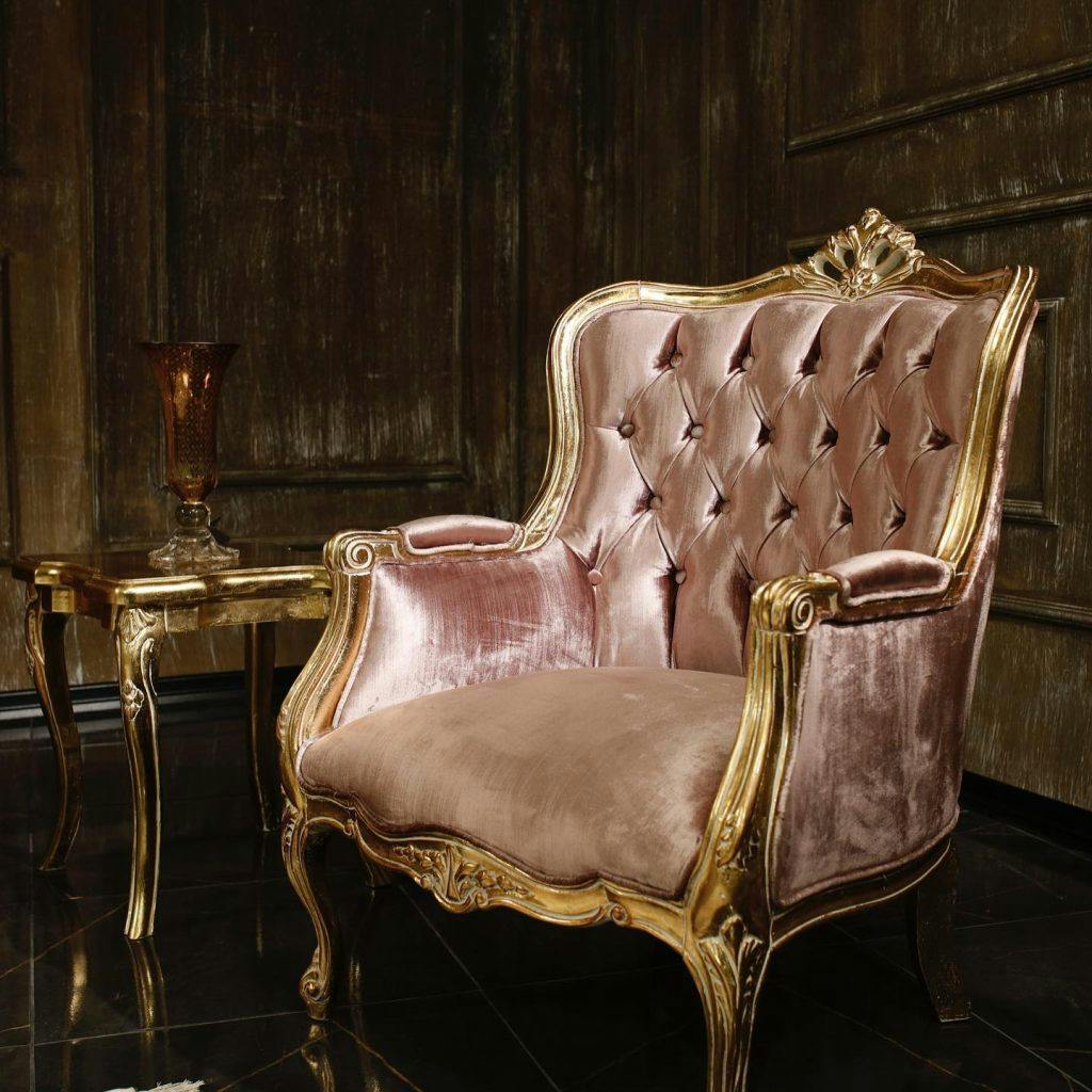 Exquisite baroque style gold-plated armchair with elaborate details and royal pink upholstery.